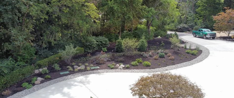 Mulched landscape bed along a driveway and woodline in Fremont, OH.