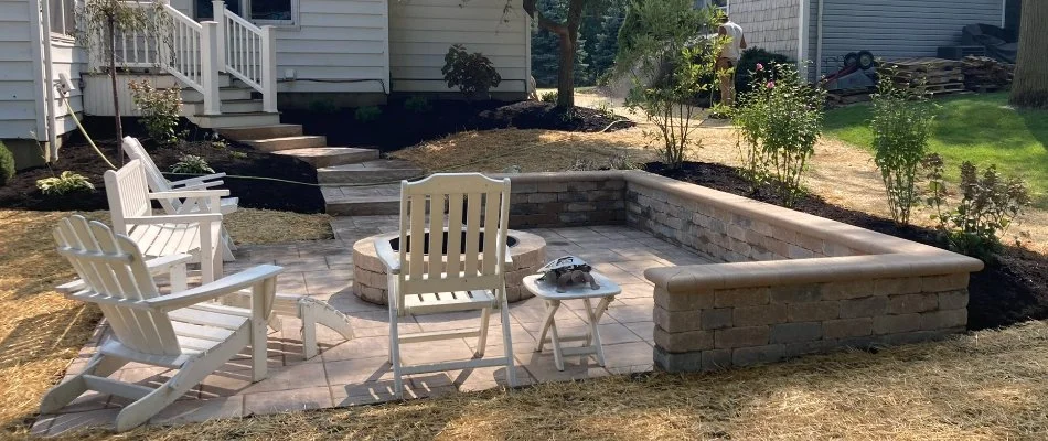 Patio in Bay Village, OH, with a seating wall, fire pit, and some chairs.