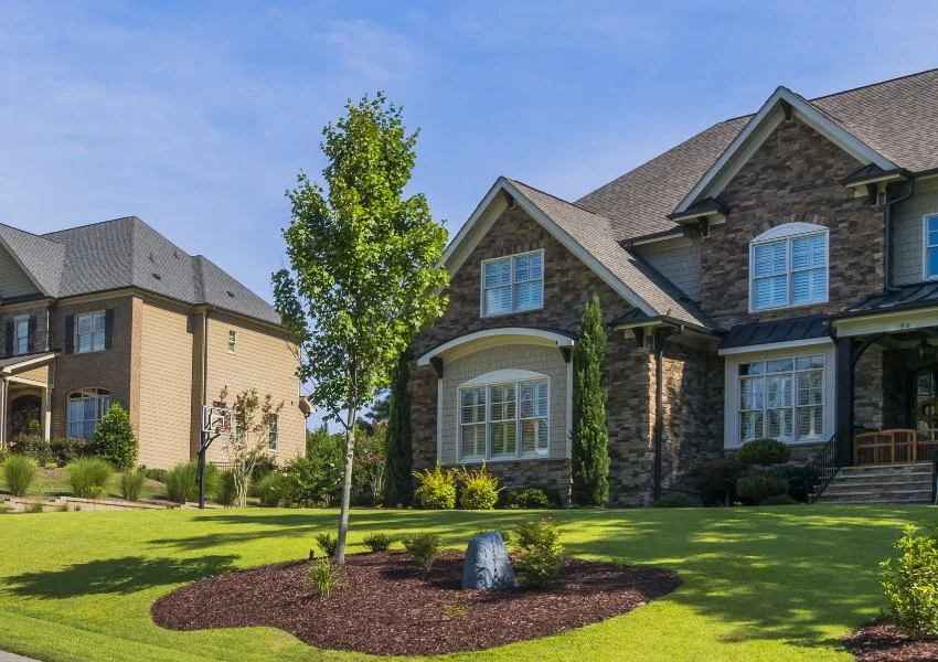 House with a nice green yard and landscape bed with a tree in Huron, OH.