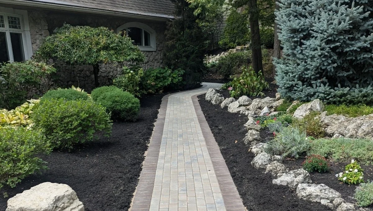 Walkway and water feature with plants in a landscape bed in front of a home in Huron, OH.