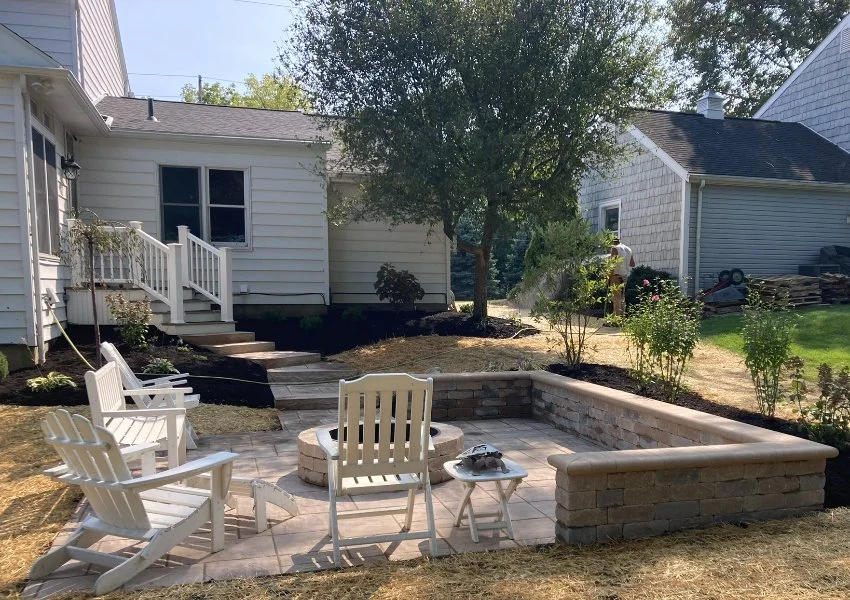 Patio with a fire pit, seating wall, and white chairs in Huron, OH.