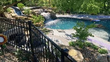 Pool area with a slide, waterfall, and landscaping.