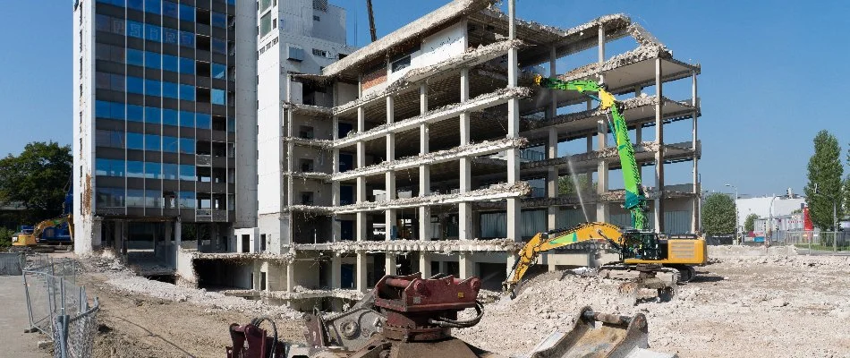 Building undergoing demolition with debris and construction equipment in action in Huron, OH.