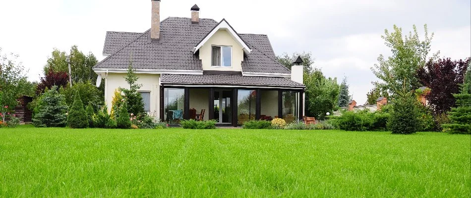 A lush, green, and well-fertilized lawn in front of a suburban house, showcasing healthy grass and vibrant landscaping in Huron, OH.