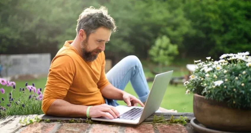 Man using laptop outdoors in garden at Huron, OH.